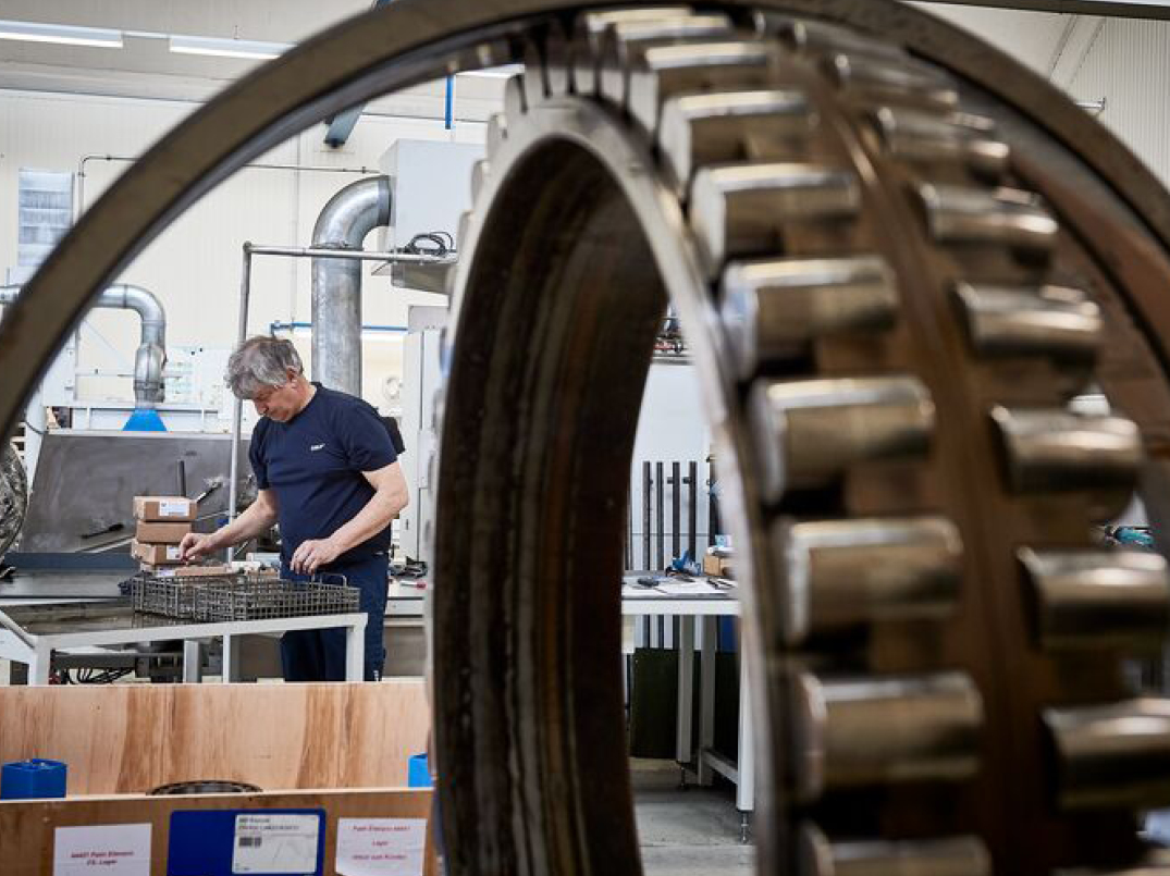 Profissional trabalhando na fábrica, visto através de um rolamento de grande porte